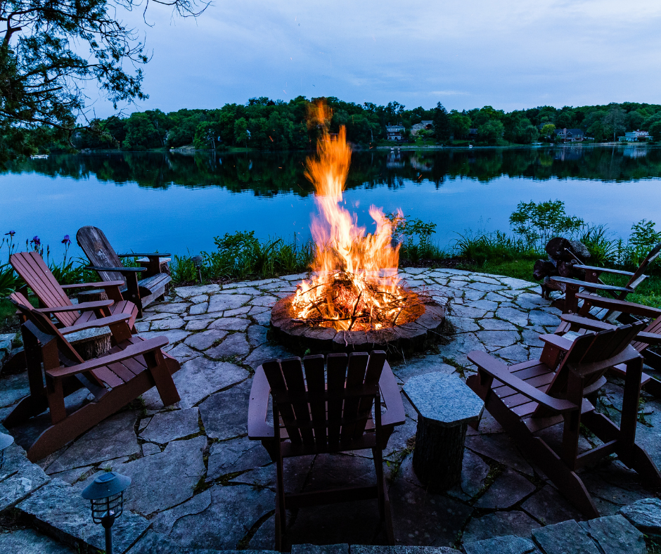 fire pit burning next to a large body of water in the woods