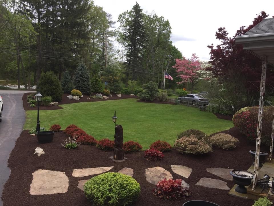 A beautiful yard with stone pavers and plantings, designed by a landscape design company - Barnstable, MA